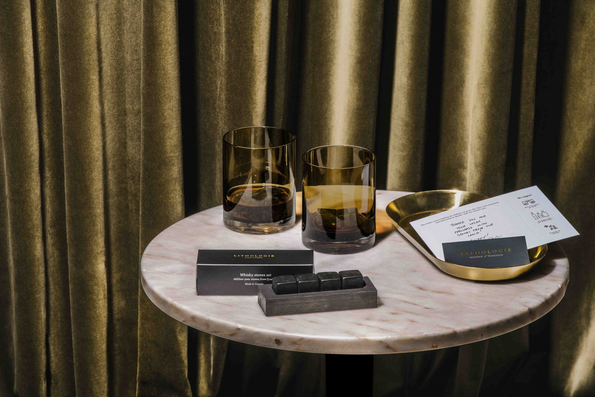 Pierres à whisky Lithologie sur une table de marbre, devant un rideau de velours